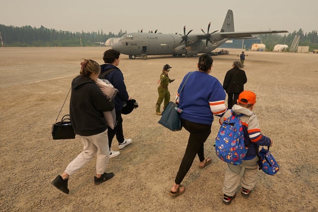 Members of the Royal Canadian Air Force help the Munroe family board a C-130 Hercules aircraft in Norway House, Man., Tuesday, June 3, 2025, at the Norway House Airport as crews continue to fight wildfires in northern Manitoba. THE CANADIAN PRESS/David Lipnowski