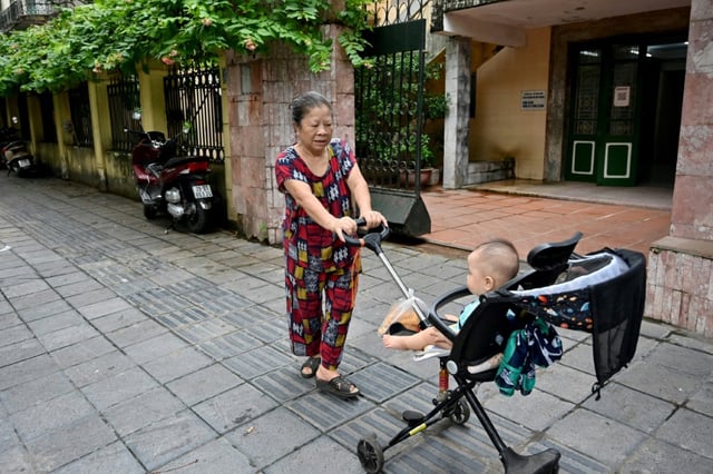 Une grand-mère promène son petit-fils dans une rue de Hanoï, le 4 juin 2025 au Vietnam