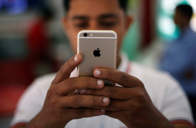A salesman checks a customer's iPhone at a mobile phone store in New Delhi, India, July 27, 2016. REUTERS/Adnan Abidi/File Photo