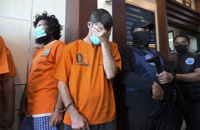 Australian national identified as P.R., second left, and an Indian national identified as H.V., left, who were arrested for drug possession, react during a National Narcotics Agency press conference in Denpasar, Bali, Indonesia Thursday, June 5, 2025. (AP Photo/Firdia Lisnawati)