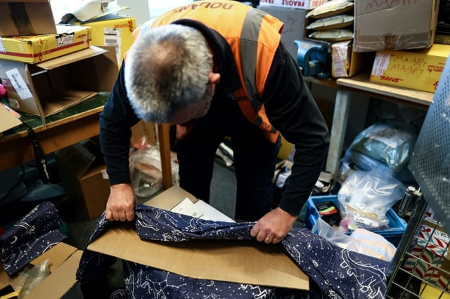 Un douanier belge ouvre un colis contenant des draps, où est cachée de la MDMA, à l'aéroport de Bruxelles le 6 avril 2023