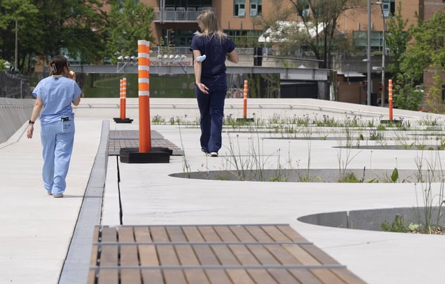Two nurses walk past markers indicating the different levels at Place des Montrealaises, a newly inaugurated public space behind city hall in Montreal on Wednesday, June 4, 2025.