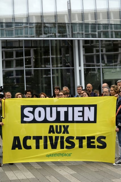 Supporters in Paris hold a banner during a rally to experss solidarity with two Greenpeace activists charged with theft