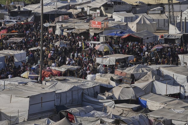 Displaced Palestinians walk trough a makeshift tent camp in Khan Younis, Gaza, on Wednesday, June 4, 2025. (AP Photo/Abdel Kareem Hana)