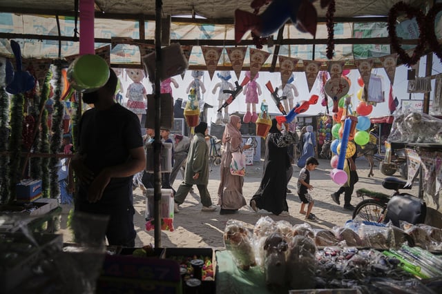 Palestinians walk past a toys shop at a market ahead of the Muslim holiday of Eid Al Adha, in Khan Younis, Gaza, Wednesday, June 4, 2025. (AP Photo/Abdel Kareem Hana)