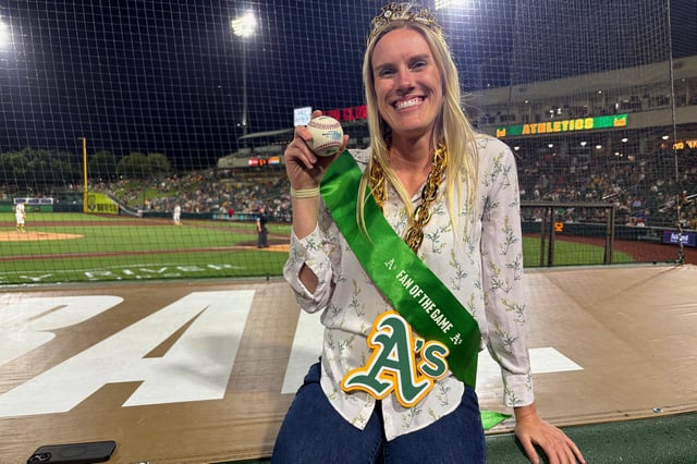 Kelly Evers shows off her “Fan of the Game” gear and the ball that she dove for during the Athletics game against the Minnesota Twins at Sutter Health Park in West Sacramento, Calif., on Wednesday, June 4, 2025. 