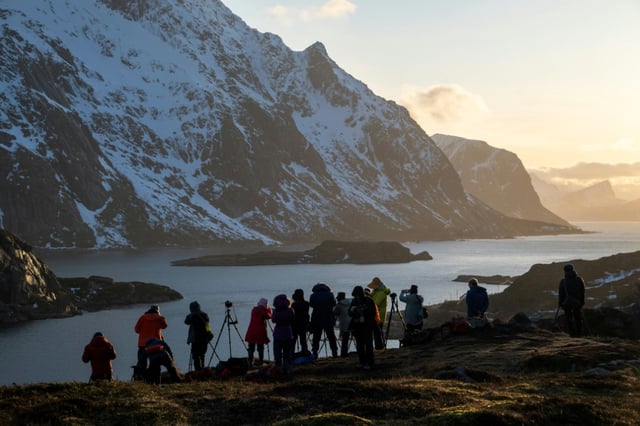 Tourists photograph a fjord in Norway's Lofoten Islands