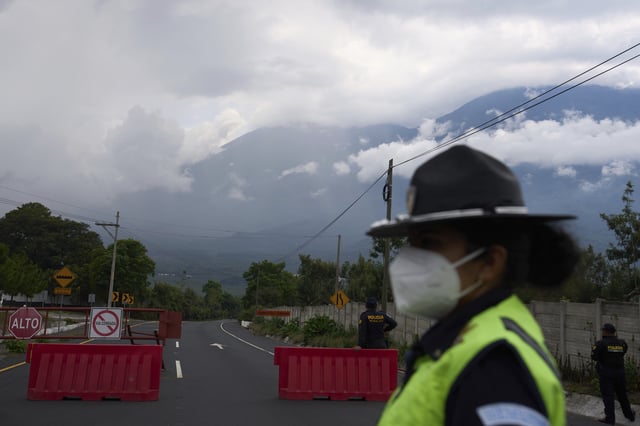 Police stand at a barricade near the Fuego Volcano in San Juan Alotenango, Guatemala, Thursday, June 5, 2025, after the volcano's explosive activity increased. (AP Photo/Moises Castillo)