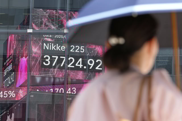 A person walks in front of an electronic stock board showing Japan's Nikkei index at a securities firm Friday, June 6, 2025, in Tokyo. (AP Photo/Eugene Hoshiko)