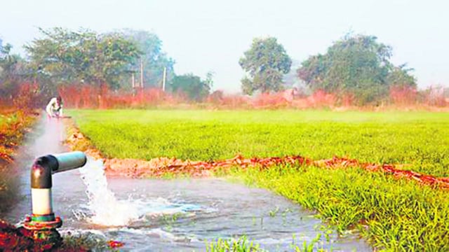 Water is flowing from a large pipe into an irrigation canal. The focus is on the water coming out of the pipe. There is wheat crop and trees in the back ground and they are blurred. (Getty Images/iStockphoto)