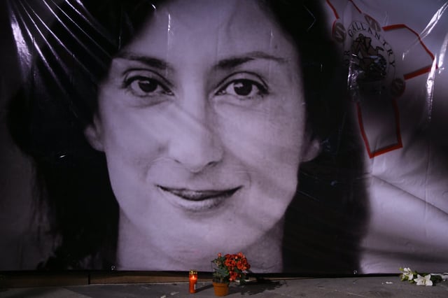 FILE - Flowers and a candle lie in front of a portrait of slain investigative journalist Daphne Caruana Galizia during a vigil outside the law courts in Valletta, Malta, Tuesday, Oct. 16, 2018. (AP Photo/Jonathan Borg, File)