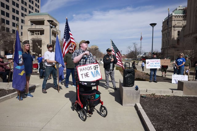 A protester wears a sign reading, "Hands off the VA," as United States military veterans and their supporters protest against the Trump administration's cuts to the Department of Veterans Affairs outside the Indiana Statehouse in Indianapolis, Indiana.
