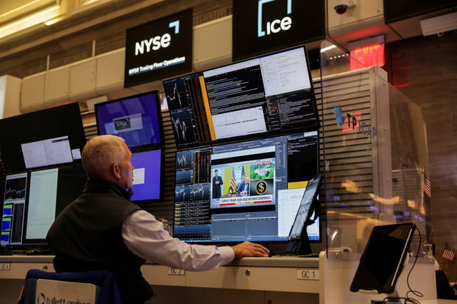 A screen shows Tesla CEO Elon Musk and U.S. President Donald Trump, as a futures-options trader works on the floor of the the New York Stock Exchange (NYSE) in New York City, U.S., May 30, 2025. REUTERS/Jeenah Moon/File Photo