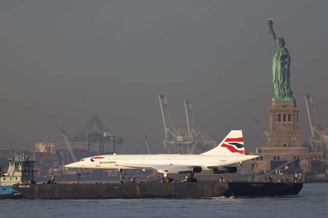 A retired British Airways Concorde supersonic airliner is moved by a barge past the Statue of Liberty on the Hudson River on March 14, 2024 in New York City.