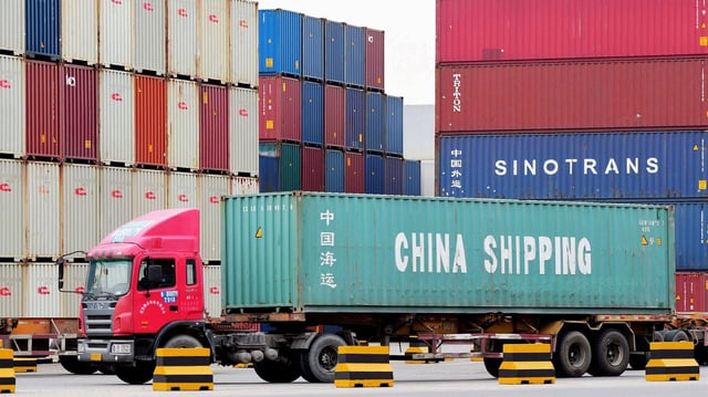 LKW mit Containern im Hafen von Qingdao, China.