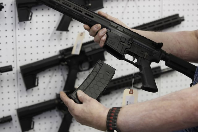 A salesperson holds a high capacity magazine for an AR-15 rifle at a store in Orem, Utah in 2021.