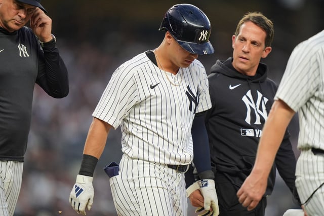 A trainer and manager Aaron Boone, left, check on Anthony Volpe after Volpe was hit by a pitch during the second inning of a baseball game against the Boston Red Sox, Friday, June 6, 2025, in New York. (AP Photo/Frank Franklin II)