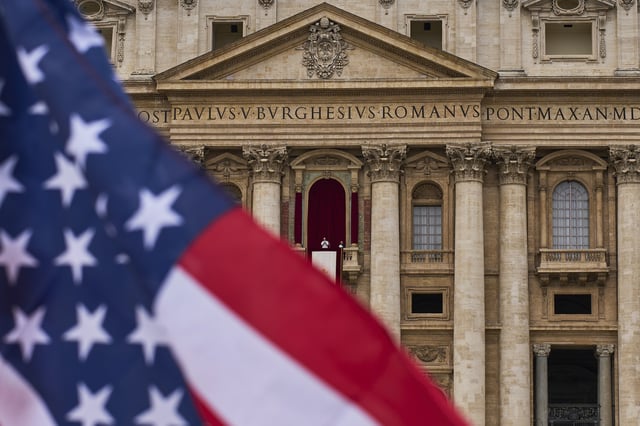 FILE - A flag from the United States waves from the crowd as Pope Leo XIV appears at the central balcony of St. Peter's Basilica for his first Sunday blessing after his election, in St. Peter's Square at the Vatican, Sunday, May 11, 2025.(AP Photo/Bernat Armangue, File)