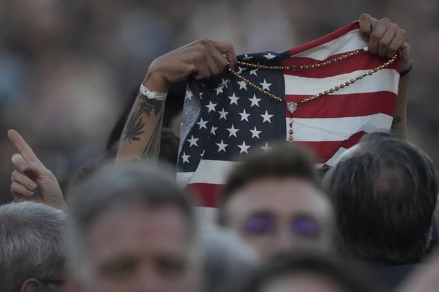 FILE - Faithful holds an American flag following the election of Pope Leo XIV at the Vatican, Thursday, May 8, 2025. (AP Photo/Andrew Medichini, File)