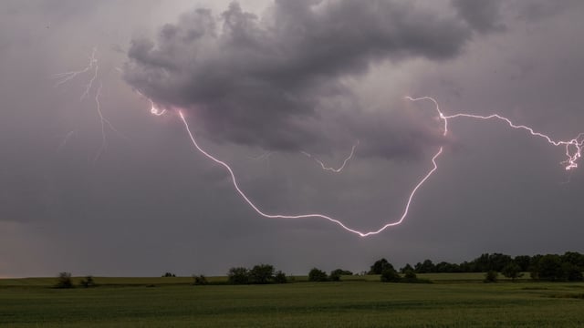 Der Blitz eines Gewitters ist über einem Feld zu sehen.