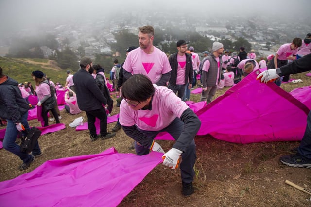Thao Le lifts a tarp to install the Pink Triangle, a symbol of hope during adversity. 