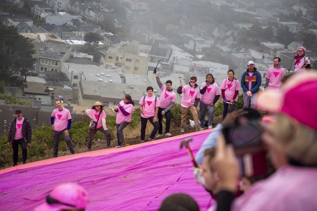 Volunteers stand on the edges of the pink triangle after installing it on Twin Peaks.