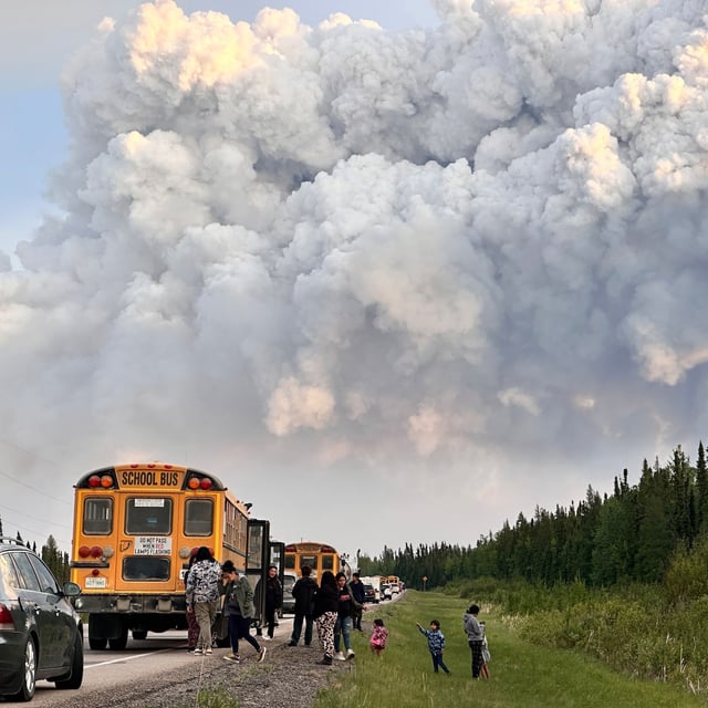 People stop along a highway as a wildfire fills the sky with smoke in the La Ronge, Sask.