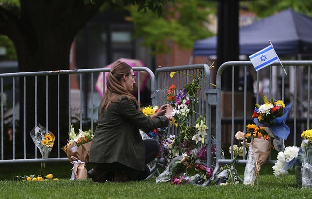 A woman places a bouquet of flowers at a makeshift memorial for victims of an attack outside of the Boulder County, Colo., courthouse Tuesday, June 3, 2025, in Boulder, Colo. (AP Photo/David Zalubowski)