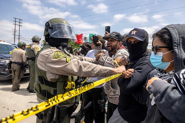 Un adjoint du shérif du comté de Los Angeles retient des manifestants après plusieurs arrestations par l’Immigration and Customs Enforcement (ICE), dans la ville de Paramount, en Californie, États-Unis, le 7 juin 2025.