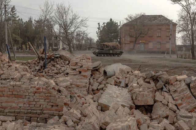 A Ukrainian tank drives on a road past buildings damaged by shelling in a village in the Dnipropetrovsk region on March 16.