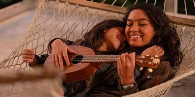 Sydney Agudong & Maia Kealoha as Nani and Lilo, lying in a hammock together and playing a ukelele in 2025's Lilo & Stitch.