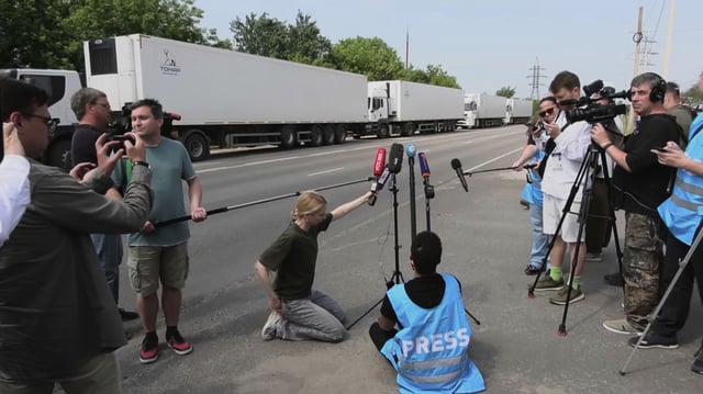 In this photo, taken from video distributed by Russian Defense Ministry Press Service on Sunday, June 8, 2025, Journalists gather near the motorcade of refrigerators of the first convoy carrying bodies of Ukrainian soldiers for repatriation at an exchange area near Novaya Guta, Belarus, for the beginning of a large-scale exchange between Russia and Ukraine. 