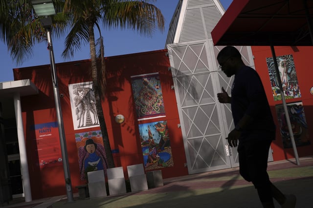 Haitian art is displayed on a wall as a man practices dance moves for a father-daughter performance organized by the Miami Police Athletic League, outside the Little Haiti Cultural Complex in Miami, Friday, June 6, 2025. (AP Photo/Rebecca Blackwell)