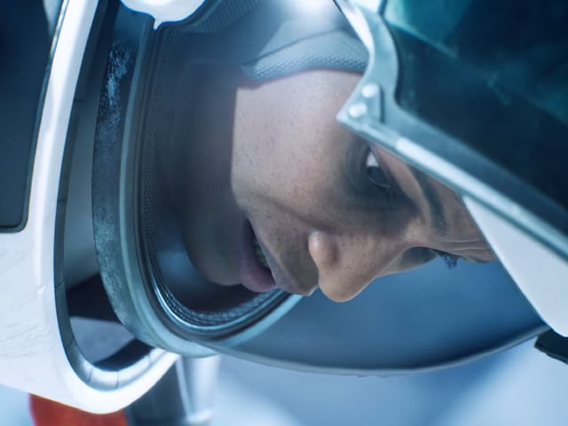 A woman in an astronaut suit looks down with a vexed expression.