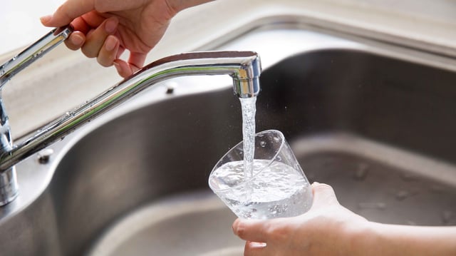 Person fills a glass with tap water from the sink.