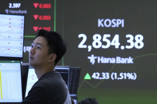A currency trader watches monitors near a screen showing the Korea Composite Stock Price Index (KOSPI) at the foreign exchange dealing room of the KEB Hana Bank headquarters in Seoul, South Korea, Monday, June 9, 2025. (AP Photo/Ahn Young-joon)