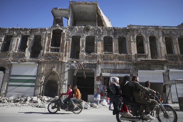 Residents drive past the war-damaged ancient market of Maarat al-Numan, near the site where a Byzantine underground tomb complex, believed to be over 1,500 years old, was uncovered by a contractor during the reconstruction of a war-damaged house, in Maarat al-Numan, Idlib suburb, Syria, on Friday, May 30, 2025. (AP Photo/Omar Albam)