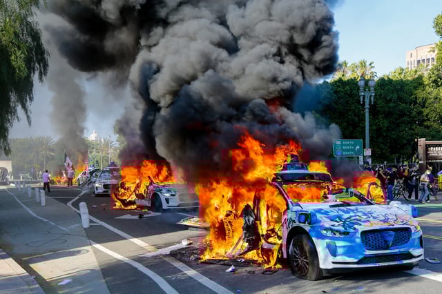 A row of Waymo vehicles burn on a street during an anti-ICE protest in downtown Los Angeles, California, on June 8, 2025.