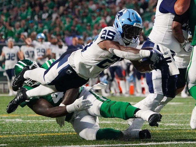 Toronto Argonauts' Ka'Deem Carey (25) dives for a touchdown as Saskatchewan Roughriders' Micah Johnson (4) defends during the second half of CFL football action in Regina, on Thursday, July 4, 2024.