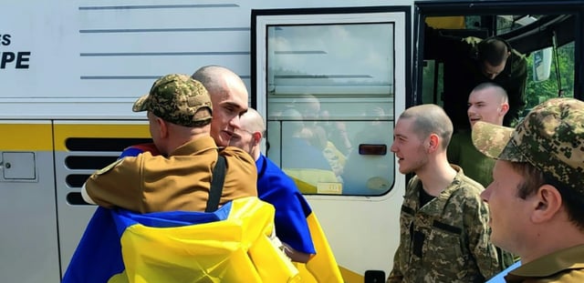 AFP - Photo prise et diffusée par le service de presse présidentiel ukrainien, le 9 juin 2025, de prisonniers de guerre ukrainiens enveloppés de drapeaux nationaux après un échange dans un lieu non divulgué