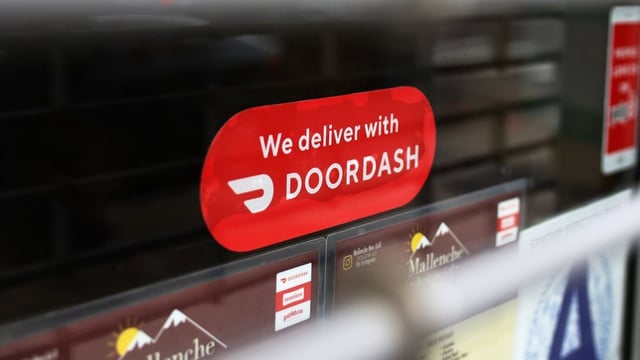 A Doordash sticker is seen on a window in Brooklyn on Dec. 4, 2020, in New York City. Canada's Competition Bureau said on Monday that it is suing the food delivery company for allegedly misleading consumers by advertising its services at a lower price than what customers actually end up paying.