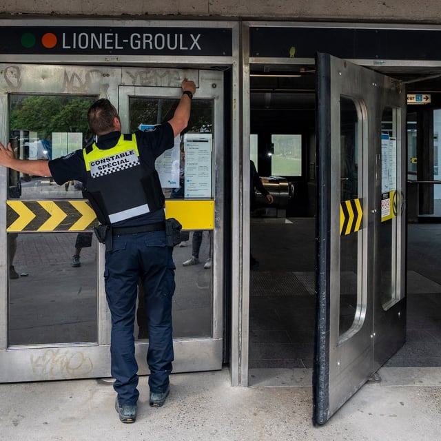 A special constable from the Société de transport de Montréal (STM) locks the doors to the metro station due to the strike from STM maintenance workers in Montreal on Monday, June 9, 2025. THE CANADIAN PRESS/Christinne Muschi