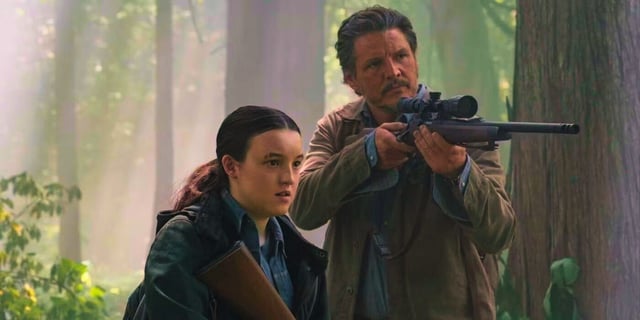 Pedro Pascal aiming a gun in the woods next to Bella Ramsey in The Last of Us