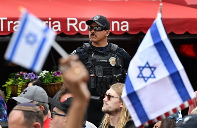 A Boulder police officer keeps an eye on the crowd during a remembrance program at the Boulder Jewish Festival on the Pearl Street Mall in Boulder on Sunday. (Helen H. Richardson/The Denver Post)