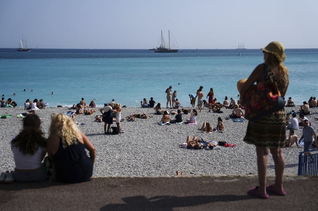 People enjoy the beach as vessels sail during the "Ocean Wonders" themed event in honor of World Oceans Day ahead of the U.N. Ocean Conference on Sunday, June 8, 2025, in Nice, France. (AP Photo/Annika Hammerschlag)
