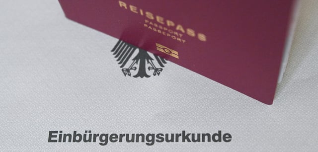 Ein deutscher Reisepass steht auf einer Einbürgerungsurkunde