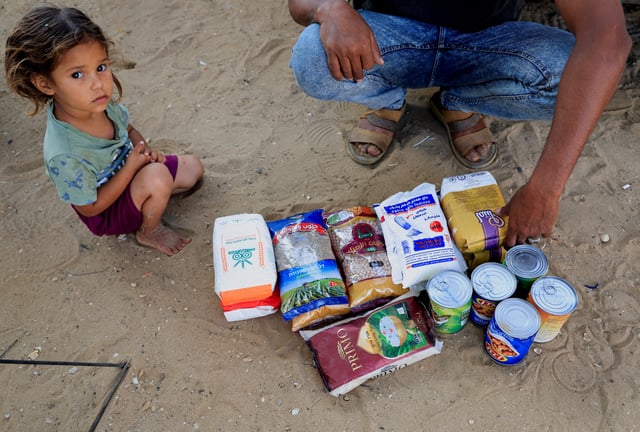 A Palestinian man, next to a child, displays the aid supplies he received from the U.S.-supported Gaza Relief Organization, in Khan Younis, southern Gaza Strip, June 5, 2025. REUTERS/Hatem Khaled