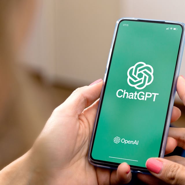 Woman using a mobile phone with ChatGPT on the screen.
