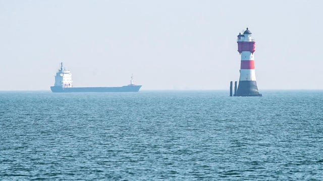 Ein Leuchtturm und ein Frachtschiff an der Nordseeküste