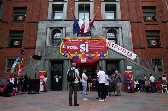 People stand next to a banner in favour of five abrogative popular referendums on employment and Italian citizenship, in Milan, Italy, June 4, 2025. REUTERS/Claudia Greco/File Photo